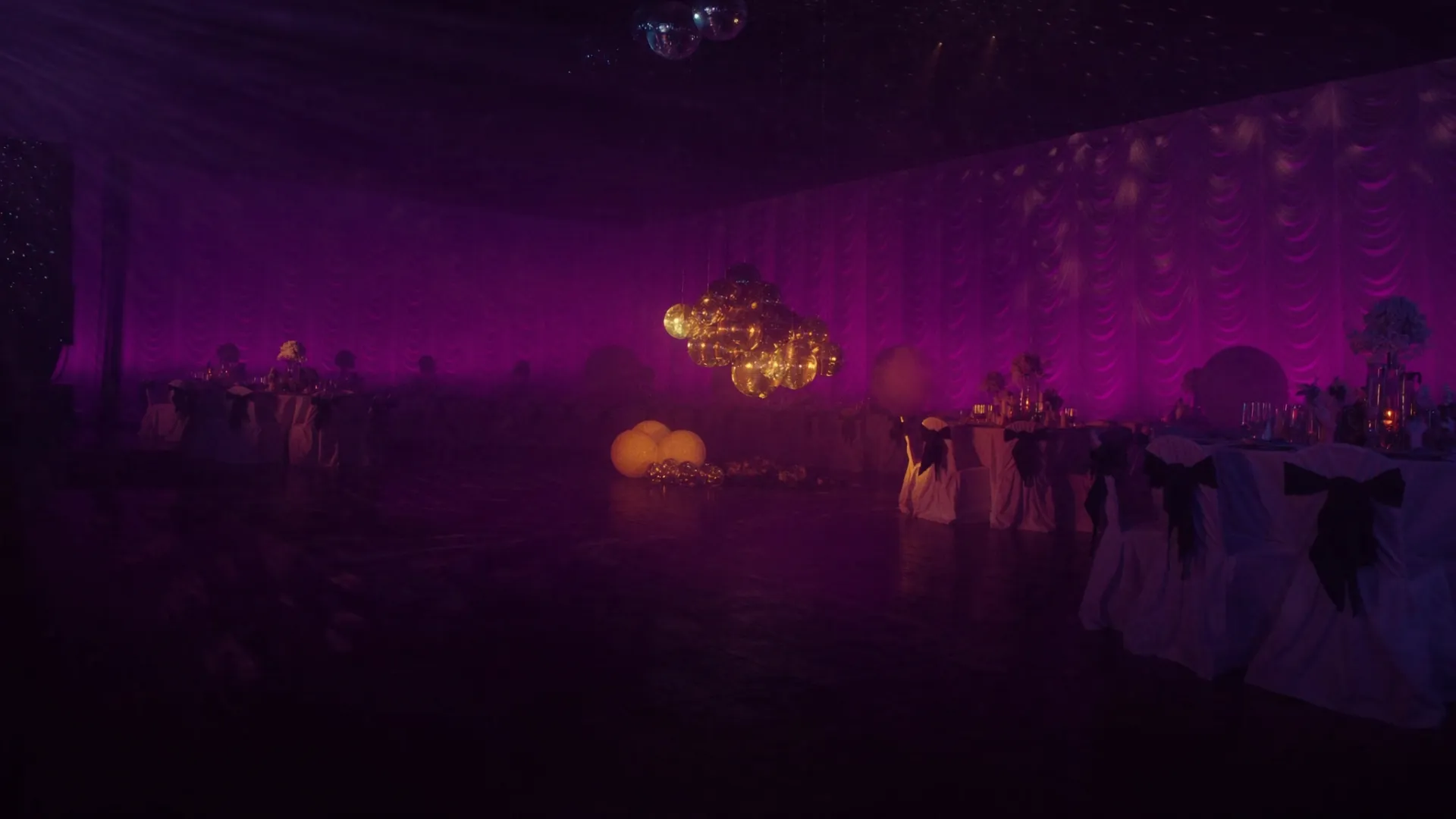 Salón de eventos Musicmix iluminado en violeta con mesas vestidas y esferas espejadas