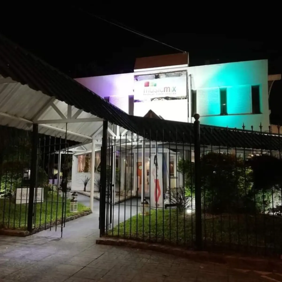 Fachada del salón de noche iluminada con luces de color y el cartel de Musicmix