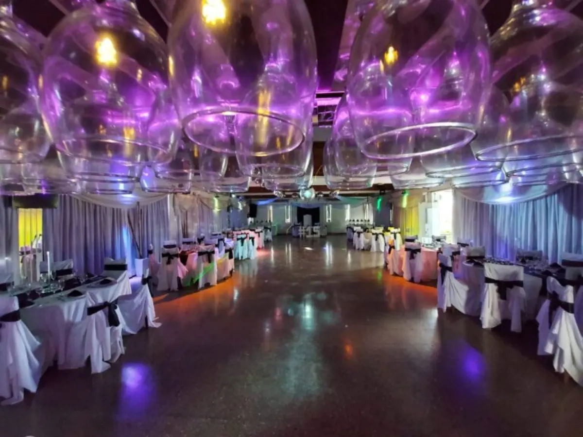Salón decorado con globos gigantes transparentes iluminados en violeta sobre la pista