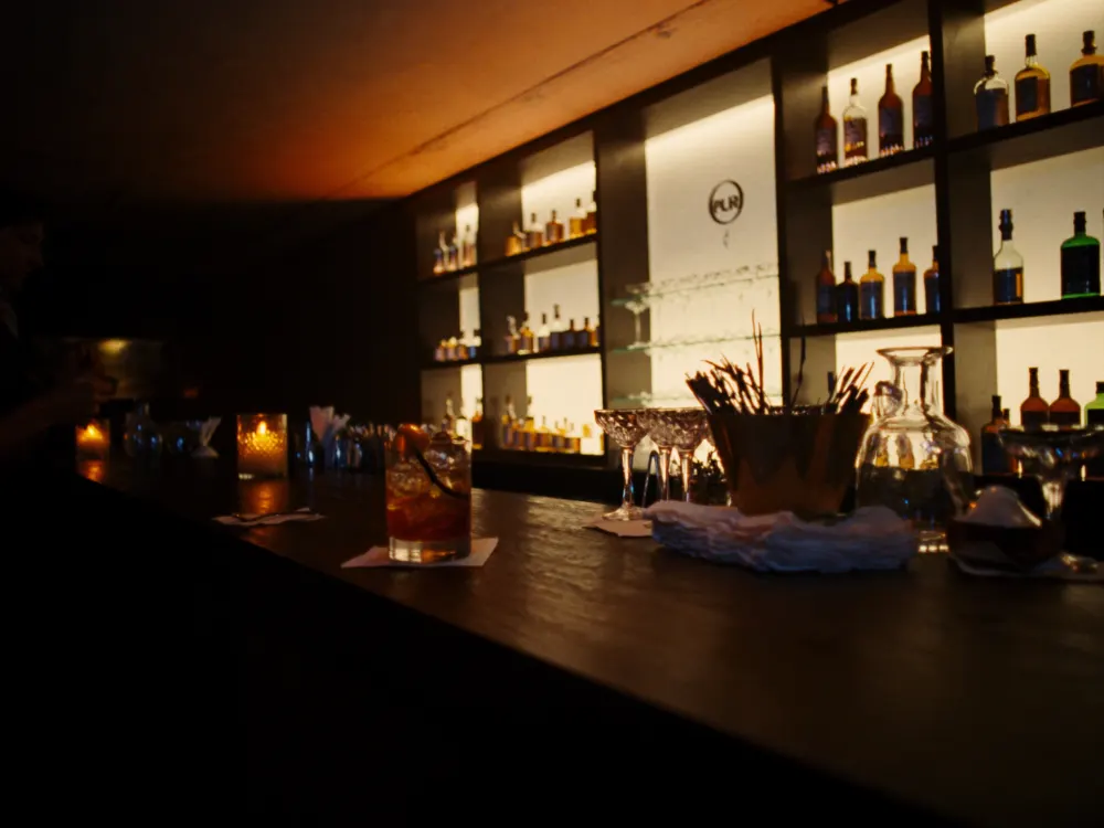 Barra iluminada con botellas y trago preparado